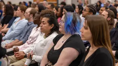 A female Wake Tech student smiles as she processes in at the start of the Phi Theta Kappa honor society induction ceremony.