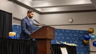 A female Wake Tech student smiles as she processes in at the start of the Phi Theta Kappa honor society induction ceremony.