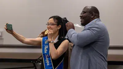 A female Wake Tech student smiles as she processes in at the start of the Phi Theta Kappa honor society induction ceremony.