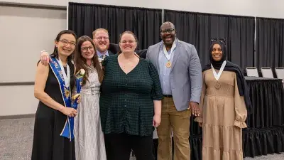 A female Wake Tech student smiles as she processes in at the start of the Phi Theta Kappa honor society induction ceremony.