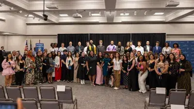 A female Wake Tech student smiles as she processes in at the start of the Phi Theta Kappa honor society induction ceremony.