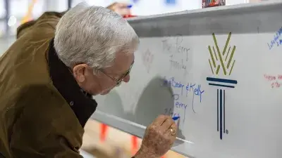 Jim Perry signs the final steel beam for the future Perry Family Simulation Hospital.