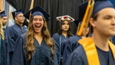 Two Wake Tech students in caps and gowns smile before their graduation ceremony.