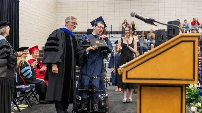 Two Wake Tech students in caps and gowns smile before their graduation ceremony.