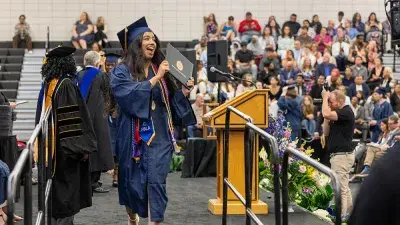 Two Wake Tech students in caps and gowns smile before their graduation ceremony.