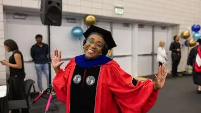 Two Wake Tech students in caps and gowns smile before their graduation ceremony.