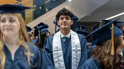 Two Wake Tech students in caps and gowns smile before their graduation ceremony.