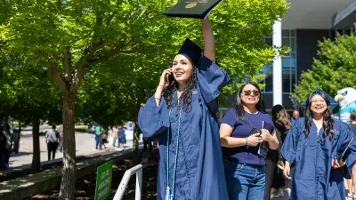 Two Wake Tech students in caps and gowns smile before their graduation ceremony.