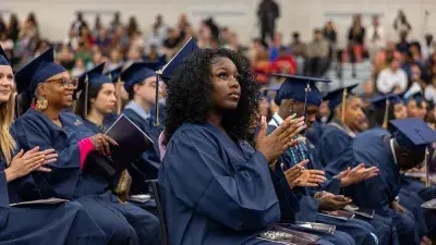Two Wake Tech students in caps and gowns smile before their graduation ceremony.