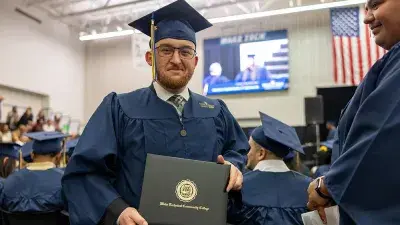 Two Wake Tech students in caps and gowns smile before their graduation ceremony.