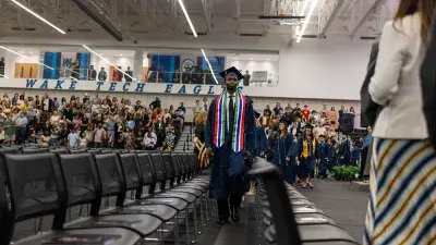 Two Wake Tech students in caps and gowns smile before their graduation ceremony.
