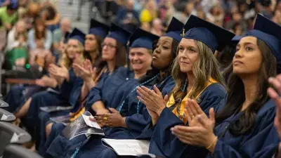 Two Wake Tech students in caps and gowns smile before their graduation ceremony.