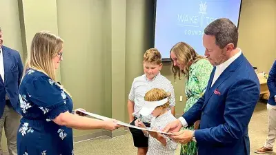 Will Smith's children sign an oversized check after announcing an endowed scholarship the Smith family created at Wake Tech.
