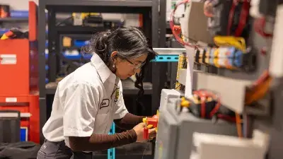 A student works on a vehicle's brakes as part of automotive systems training.