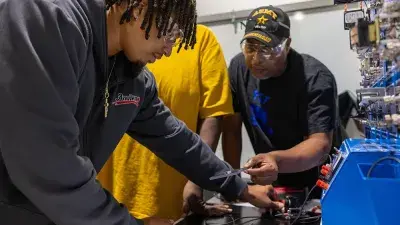 A student works on a vehicle's brakes as part of automotive systems training.