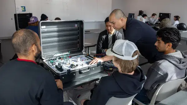 Alex Tang works with Automotive Systems Technology students on an electrical wiring exercise.