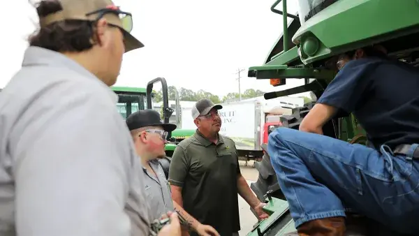 Assistant Professor Chris Keeler observes as students work on a John Deere combine.