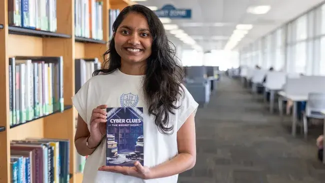 Neha Amaraneni poses with her book in the Wake Tech Library.